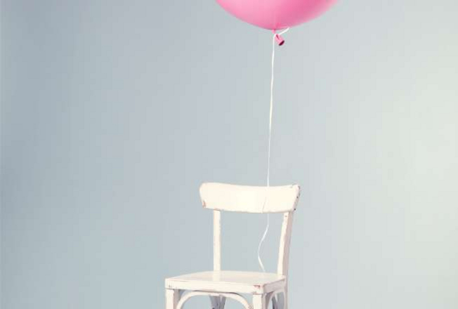 Rosa Luftballon an einem weißen Stuhl