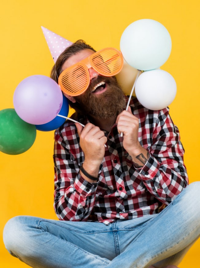 Fröhlicher Mann mit großer Brille und Ballons