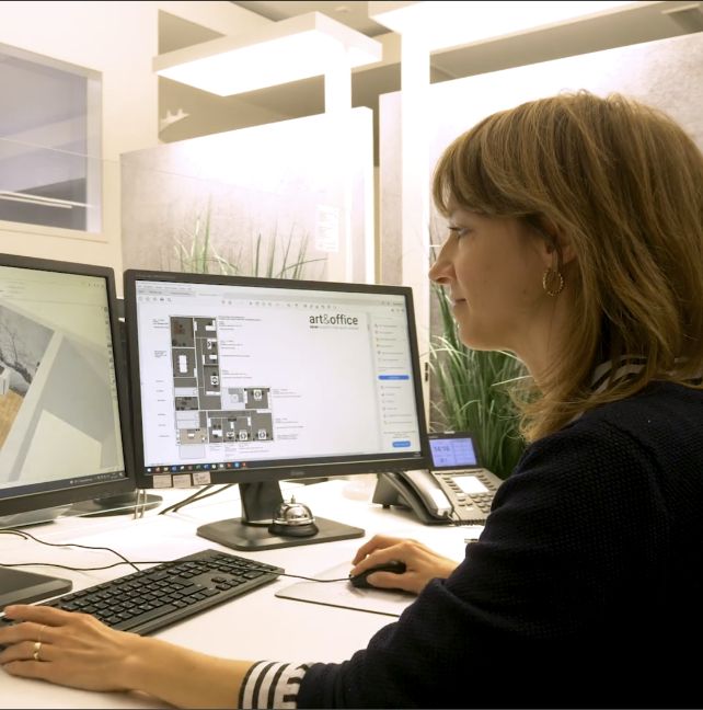 Frau sitzt vor zwei Bildschirmen