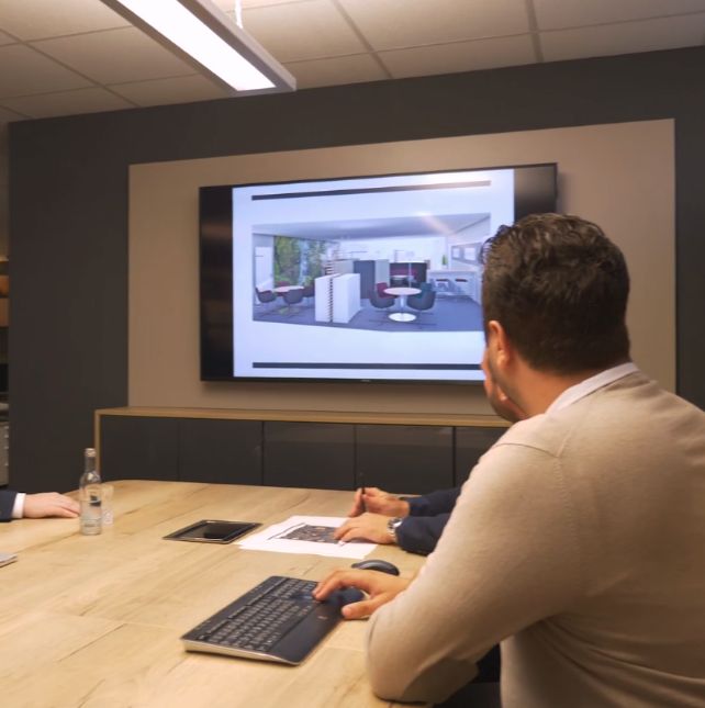 Mehrere Personen schauen auf einen Monitor mit Raumplanung