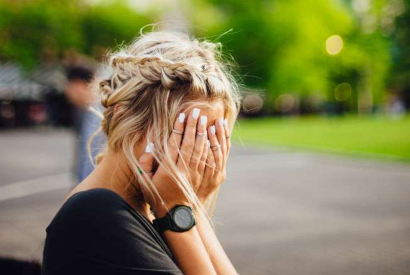 Frau versteckt ihr Gesicht in ihren Händen